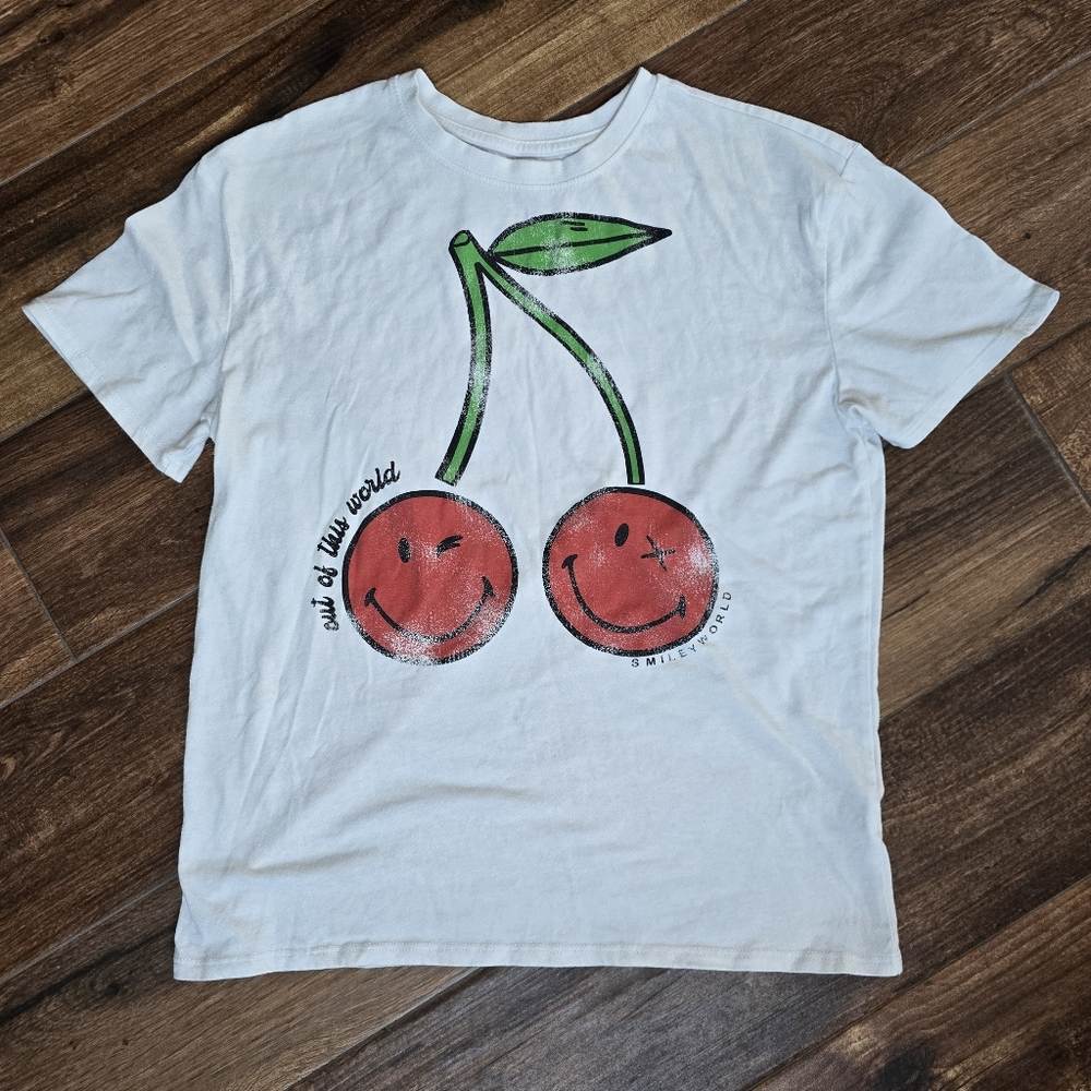 SmileyWorld T-shirt with a cherry graphic and the text "out of this world".